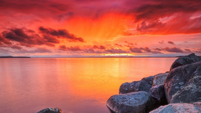 Sunset over a calm lake with rocks in the foreground