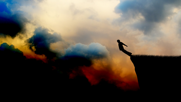 Silhouette of a person jumping off a cliff