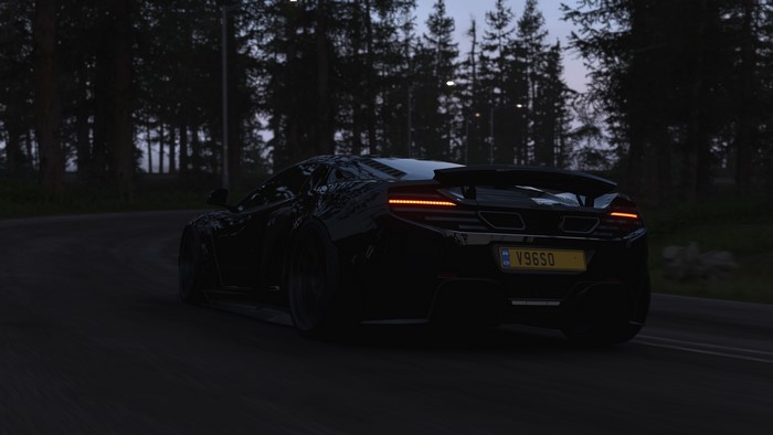Black McLaren sports car on a road at dusk