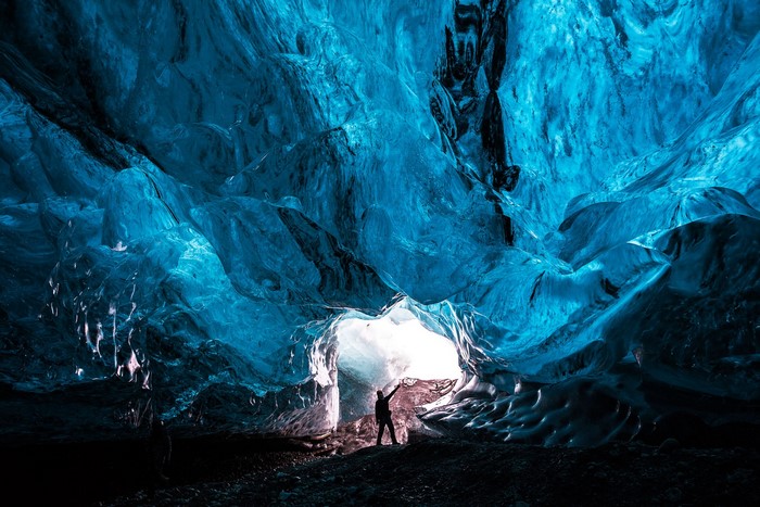 Person inside a glowing blue ice cave