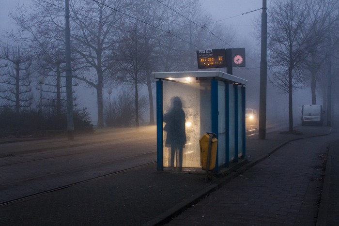 Person waiting at a foggy bus stop