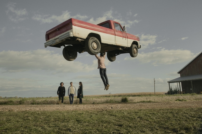 Superman holding a truck with Lois Lane and Clark Kent watching