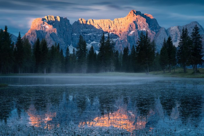 Mountain range reflected in a misty lake at sunrise