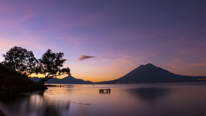 Sunset over Lake Atitlán with volcanoes and trees