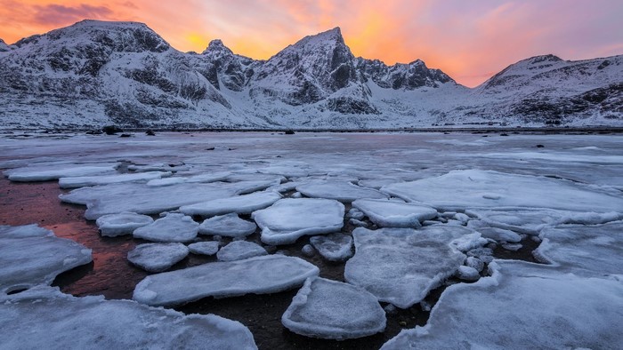 Snowy mountains at dawn over a frozen lake in Lofoten Islands, Norway