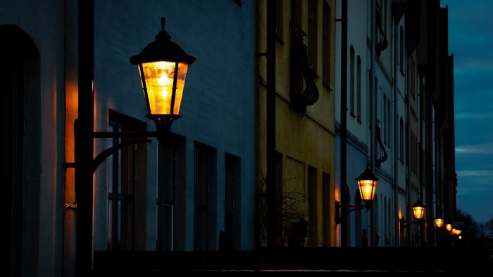 Street lamps illuminate buildings at dusk