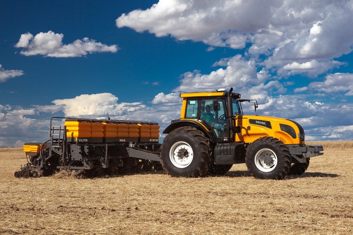 Yellow Valtra tractor pulling a planter in a field