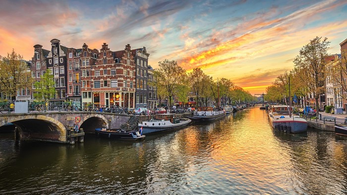 Amsterdam canal with boats and buildings at sunset