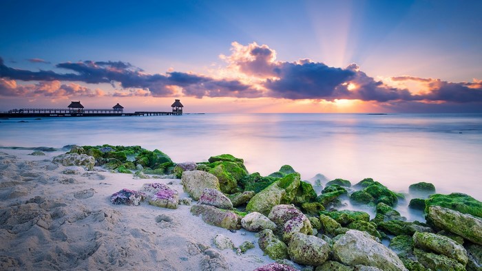 Sunrise over the Caribbean Sea with a pier and rocks