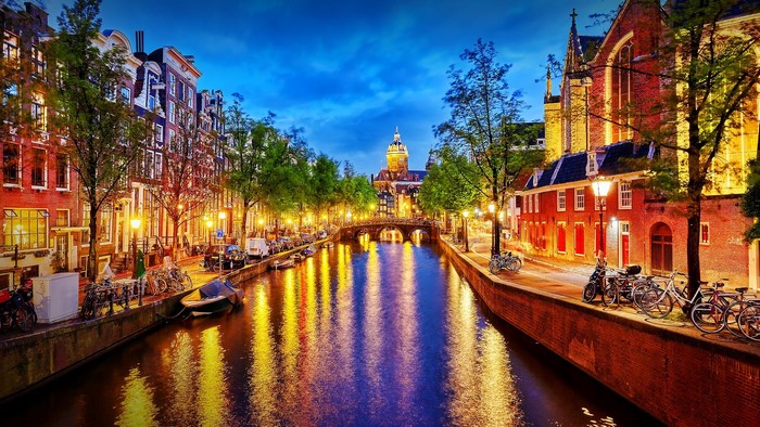 Amsterdam canal at night with bridge and buildings