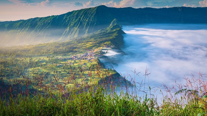 Village nestled in mountains above clouds in Indonesia