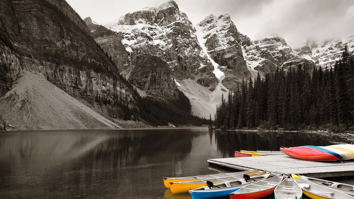 Canoes docked at Moraine Lake with snowy mountains