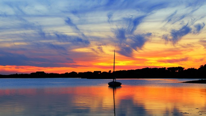 Sailboat on a lake at sunset with colorful clouds