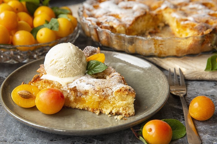 Slice of apricot pie with ice cream and fresh apricots