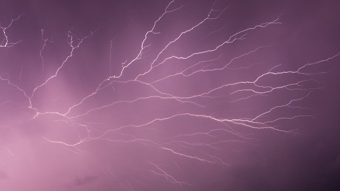 Lightning strikes across a purple night sky