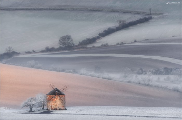 Windmill on snow-covered hills by Vlad Sokolovsky