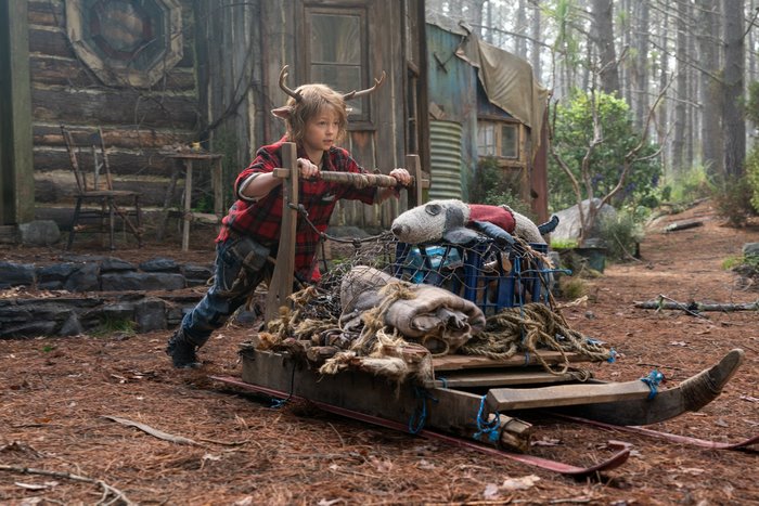 Gus (Sweet Tooth) pushing a sled in the woods