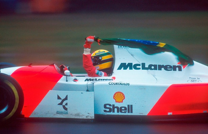 Ayrton Senna driving a McLaren Formula 1 car with Brazilian flag