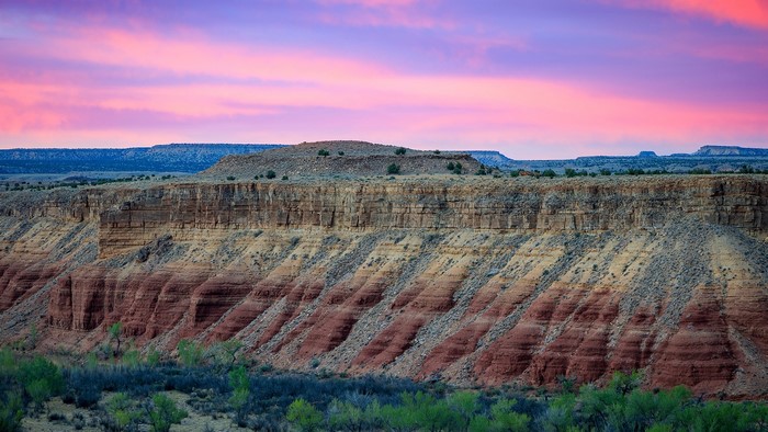 Layered rock formations at sunrise with colorful sky