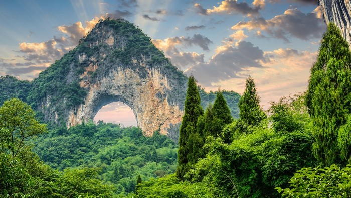 Mountain arch with trees and sun rays in China
