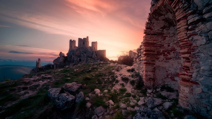 Ruin castle on a rocky hill at sunset