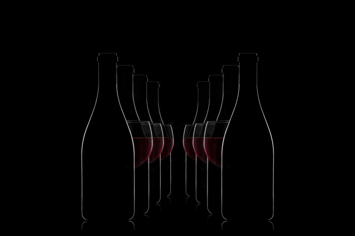 Bottles and glasses of red wine on a black background