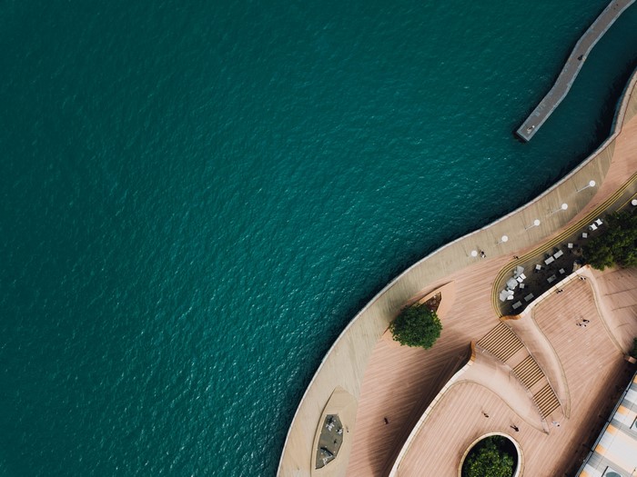 Aerial view of a modern waterfront promenade and teal water