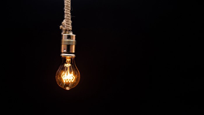 Light bulb hanging from rope on black background