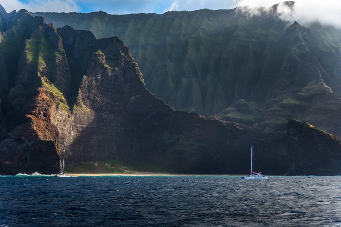 Catamaran sailing near Napali Coast mountains, Hawaii