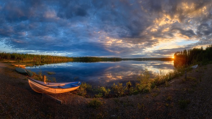 Boats on the shore of a lake at sunset