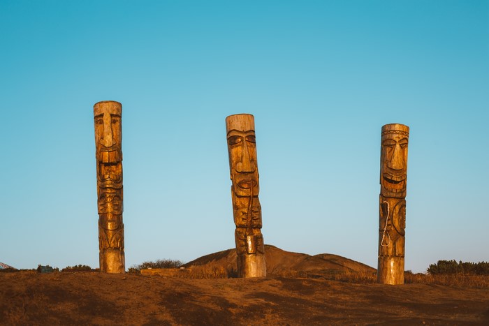 Three wooden totem poles on a grassy hill