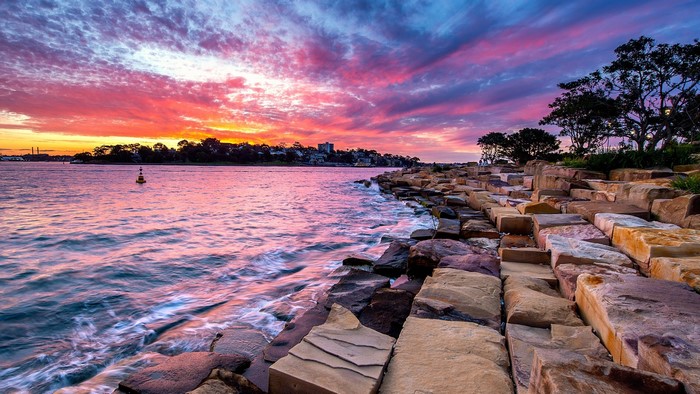 Sunset over water with rocks and trees in Sydney