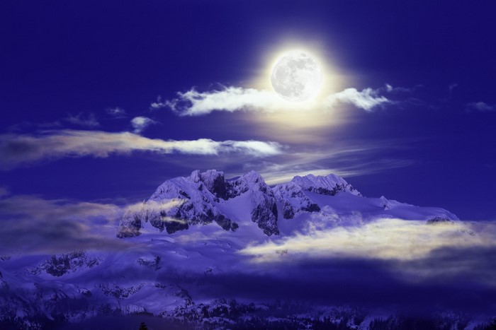 Full moon over snow-capped mountains at night