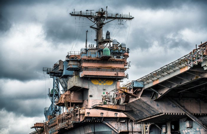 Decommissioned aircraft carrier under a cloudy sky