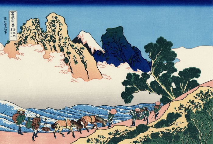 Travelers and pack animals on a mountain path with Mount Fuji