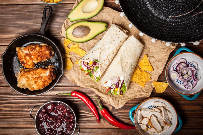 Mexican food spread with tortillas, chicken, and avocado