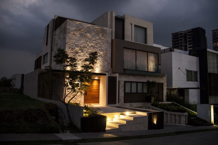 Modern mansion with stone facade and wooden door at night