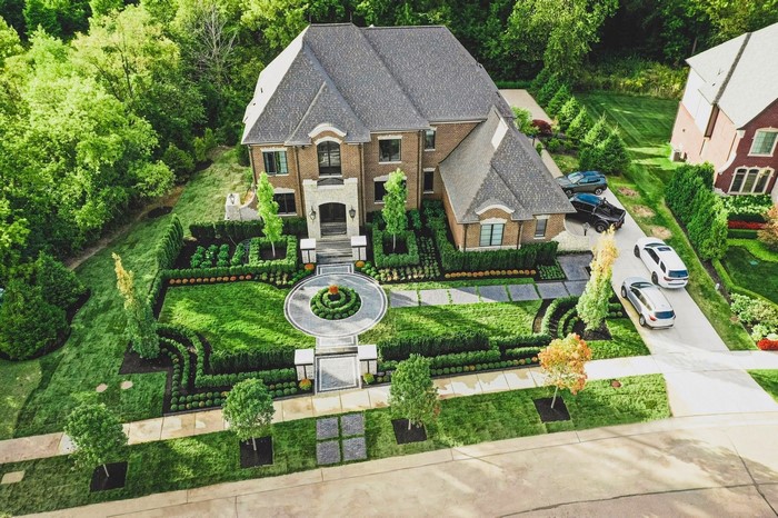Luxury brick house with manicured gardens and cars