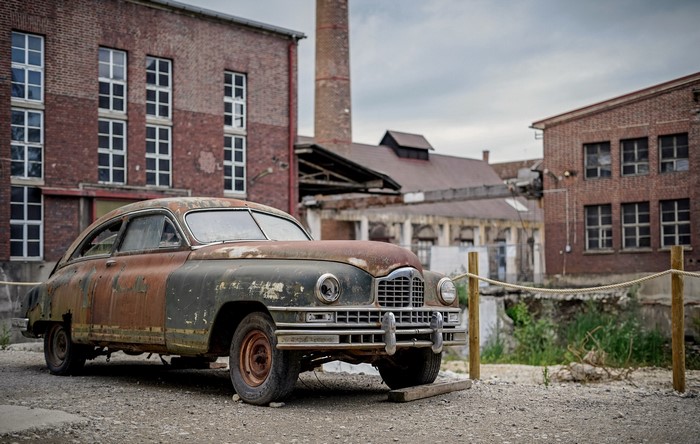 Rusted vintage car in front of abandoned brick factory
