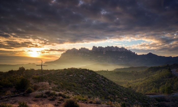 Sunrise over misty mountains with a cross