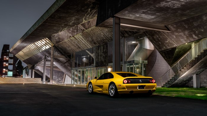 Yellow Ferrari F355 parked at modern building at night