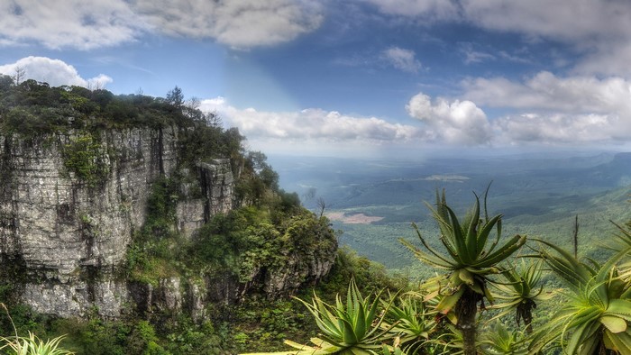 Panoramic view of a rocky cliff overlooking a vast green valley