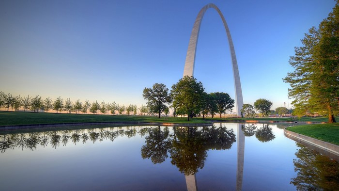 Gateway Arch reflected in water with trees and sky