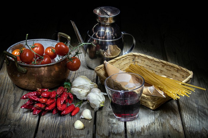 Still life of tomatoes, peppers, garlic, spaghetti, and wine