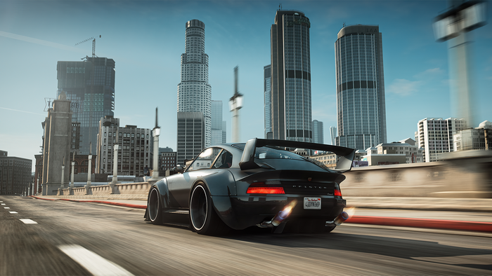 Black sports car with spoiler driving on a city road