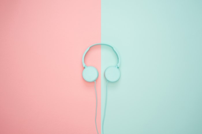 Light blue headphones on pink and teal background