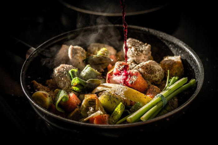 Meat and vegetables cooking in a pan with red wine