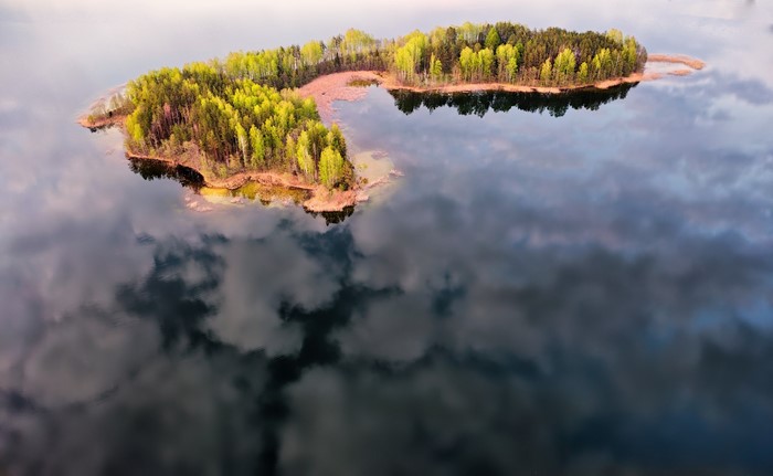Aerial view of an island with trees reflected in the water