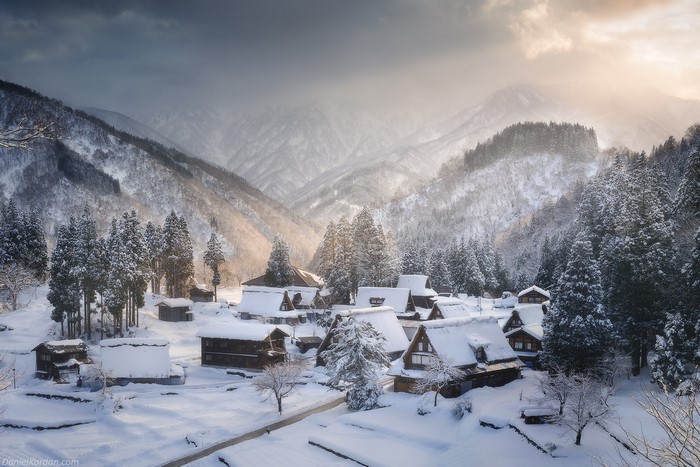 Snowy Japanese village in mountains with sun rays