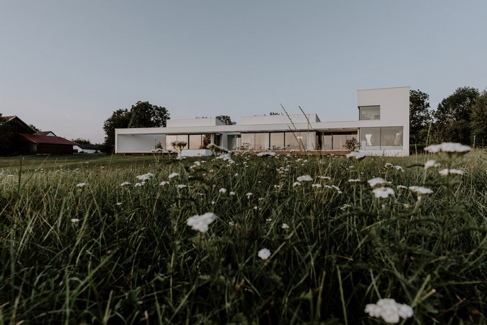 Modern white house with large windows in a grassy field